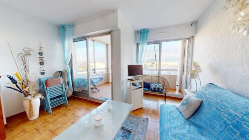 un salon avec un canapé bleu et une table dans l'établissement appartement 4 personnes vue sur la marina, à Canet