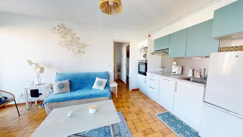 un salon avec un canapé bleu et une cuisine dans l'établissement appartement 4 personnes vue sur la marina, à Canet