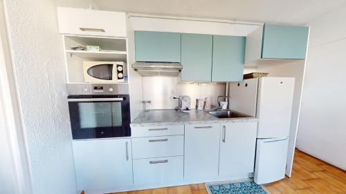 une cuisine avec des armoires blanches et un réfrigérateur blanc dans l'établissement appartement 4 personnes vue sur la marina, à Canet