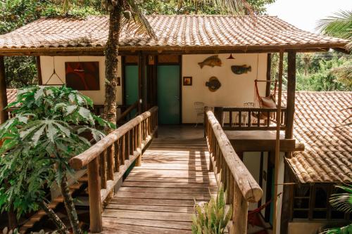 a wooden walkway leading to a house with a roof at Atelier Arte Paraty Mirim in Paraty