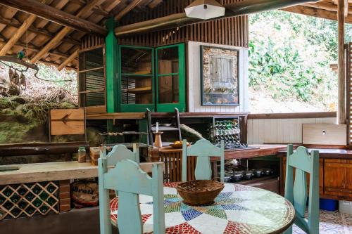 a kitchen with a table and some green cabinets at Atelier Arte Paraty Mirim in Paraty