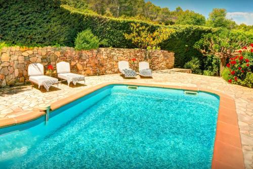 a swimming pool with chairs and a stone wall at Maison Lou Amourier - OVO Network in Cotignac