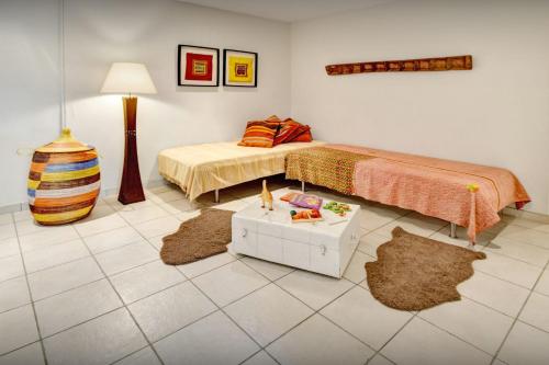 a bedroom with two beds and a table with rugs at Maison Lou Amourier - OVO Network in Cotignac