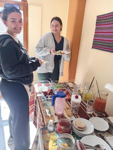 two women standing in front of a table with food at Marlon's House Puno-Peru in Puno
