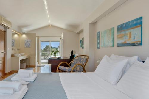 a bedroom with a large white bed and a desk at Artemida Beach House in Artemida