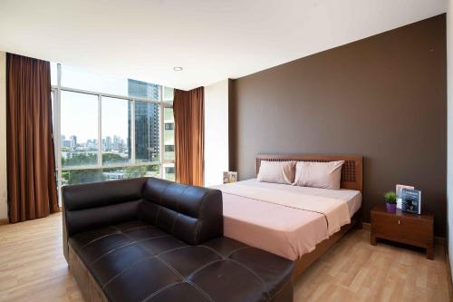 a bedroom with a bed and a leather couch at 181 Ekkamai Apartment in Bangkok