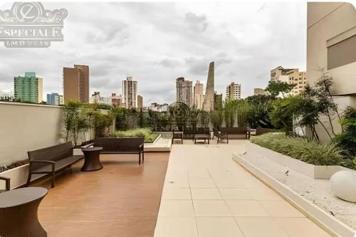 a rooftop patio with benches and a city skyline at Temático,moderno e com pôr do sol Mueller/Centro in Curitiba