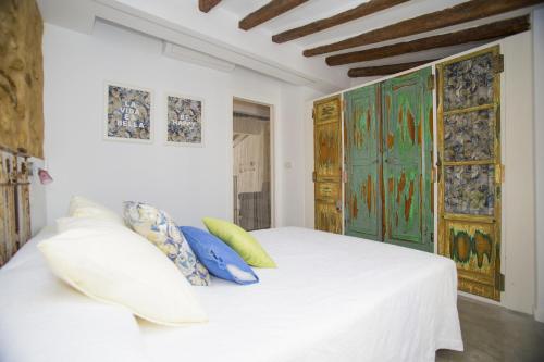 a bedroom with a white bed with blue and yellow pillows at HappyVila SUITE APARTMENTS in Villajoyosa