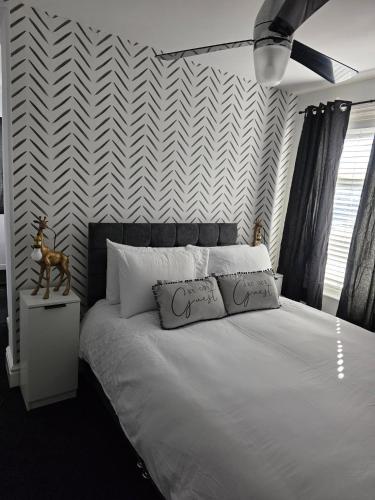 a bedroom with a white bed with a chevron wall at Bluebell Hotel in Blackpool