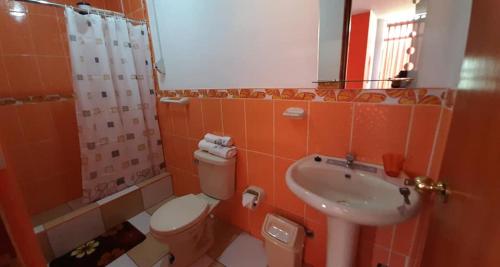 an orange bathroom with a toilet and a sink at Marlon's House Puno-Peru in Puno