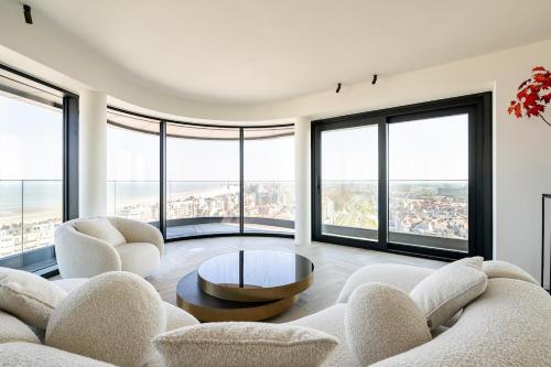 a living room with white furniture and large windows at Unique penthouse with sublime sea views in Knokke-Heist