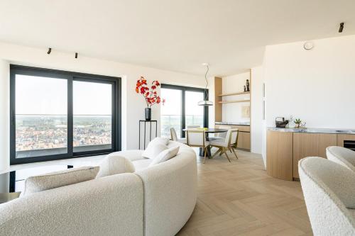 a living room with two white couches and a kitchen at Unique penthouse with sublime sea views in Knokke-Heist