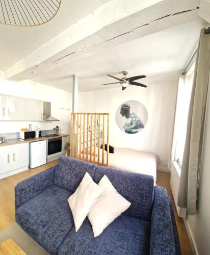 un salon avec un canapé bleu et une cuisine dans l'établissement Les Bons Enfants 2, à Rouen