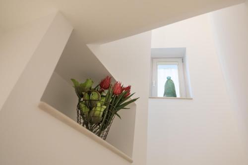 a vase of flowers in a room with a window at Dimore Trulli Holiday in Alberobello