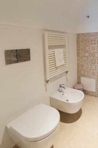 a white bathroom with a toilet and a sink at Dimore Trulli Holiday in Alberobello