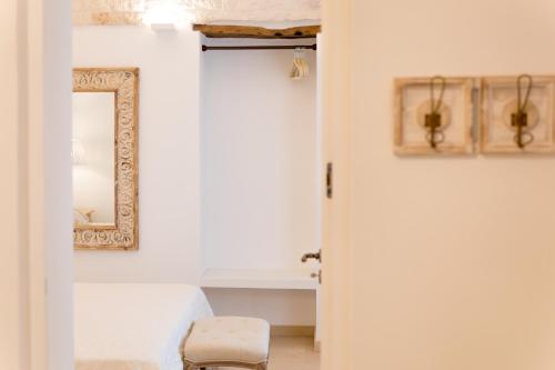 a bathroom with a mirror and a stool next to a sink at Dimore Trulli Holiday in Alberobello