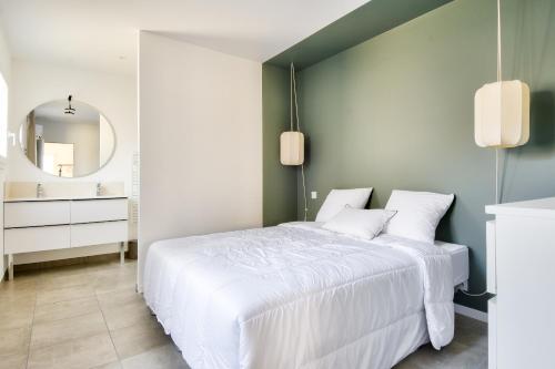 ein Schlafzimmer mit einem weißen Bett und einem Spiegel in der Unterkunft Belle maison pour 8 - 350m de la plage - Terrasse in La Guérinière