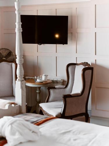 a bedroom with a bed and two chairs and a table at Old Court House Inn in Saint Aubin