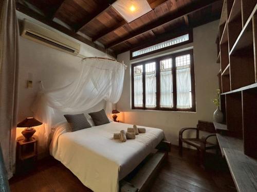 a bedroom with a white bed in a room with windows at Yellow House in Bangkok