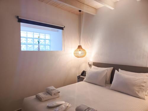 a bedroom with a bed with white sheets and a window at Evge Experience Boutique Hotel in Kafoúros