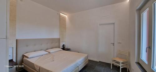 a white bedroom with a bed and a chair at Un'oasi tra i limoni in Naso