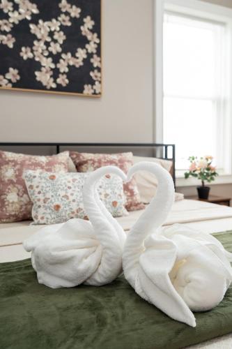 two white swans sitting on top of a bed at 558-1 Boston - Spacious & Modern 3BR near Franklin Park in Boston