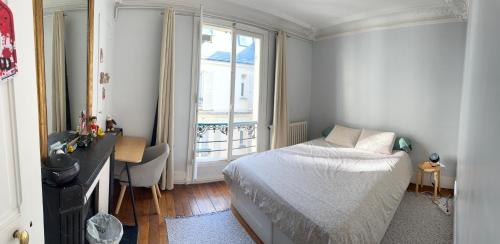 une petite chambre avec un lit et une fenêtre dans l'établissement Appartement muette, à Paris