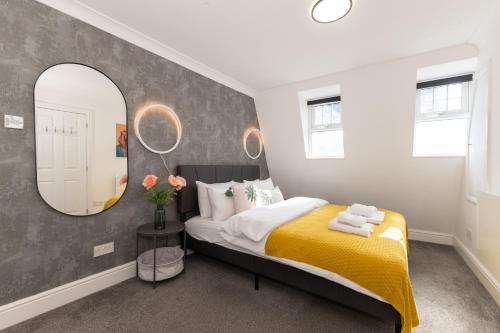 a bedroom with a yellow bed and a mirror at The Cottage in Woolwich