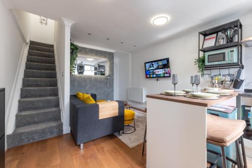 a kitchen and living room with a bar and a staircase at The Cottage in Woolwich