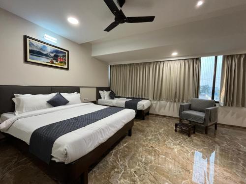 a hotel room with two beds and a chair at Kuber Suites in Solapur