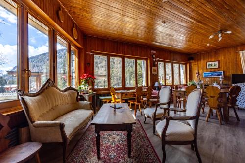 a living room with chairs and tables and windows at Hotel Le Campagnol in Champoluc