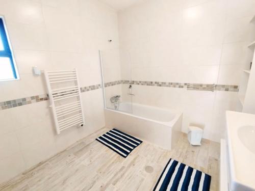 a white bathroom with a tub and a sink at Quinta Azul in Loulé