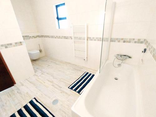a white bathroom with a tub and a toilet at Quinta Azul in Loulé