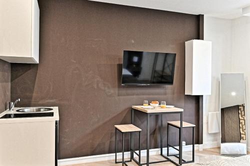 Il comprend une cuisine avec un comptoir et une télévision murale. dans l'établissement Studio Élégant Paris - Père Lachaise, à Paris