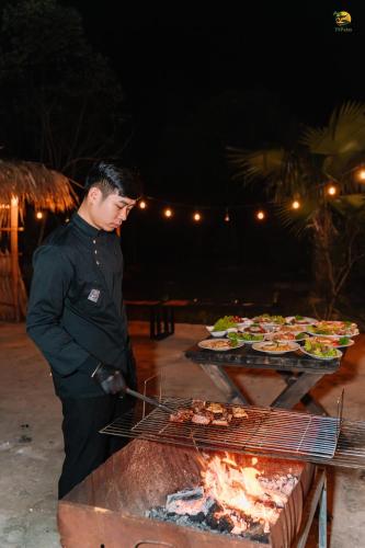 a man is cooking food on a grill at TVpalm Ecolodge in Ha Giang