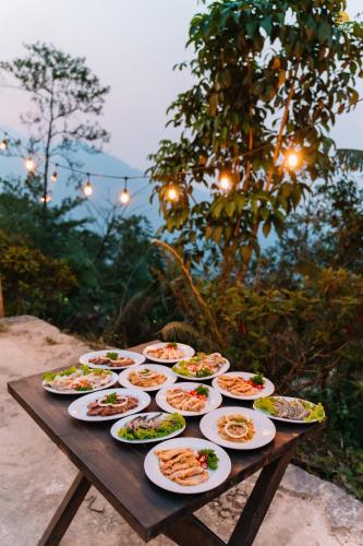 a wooden table with plates of food on it at TVpalm Ecolodge in Ha Giang