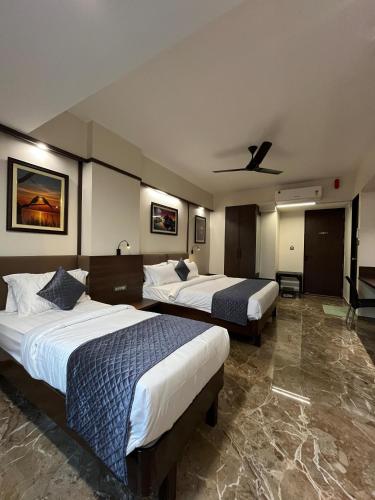a hotel room with two beds and a ceiling fan at Kuber Suites in Solapur