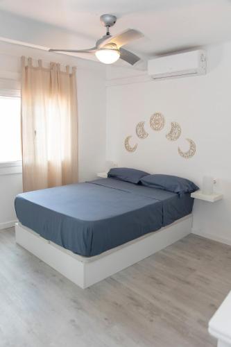 a bedroom with a bed with blue sheets and a ceiling fan at Seahomes Vacations - Center Apt Tossa de Mar in Tossa de Mar