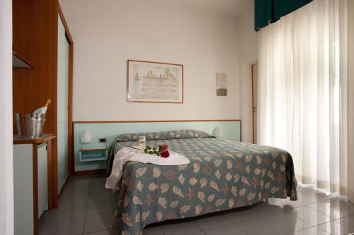 a bedroom with a bed and a table with flowers on it at Hotel Gaby in Rimini