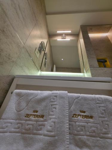 a bathroom with two white towels in front of a shower at Apartmani Zepterme by CENTRAL in Vrnjačka Banja