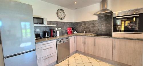 une cuisine avec des armoires en bois et une horloge au mur dans l'établissement Gîte Le Tuquet Ideal Stay in Purple Périgord Nature & Tranquility, à Rampieux