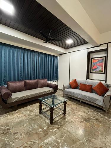 a living room with two couches and a table at Kuber Suites in Solapur