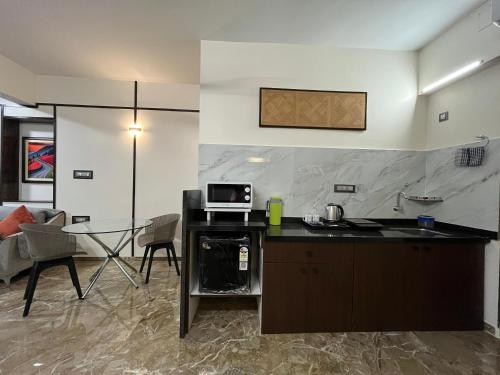 a kitchen and living room with a table and a microwave at Kuber Suites in Solapur