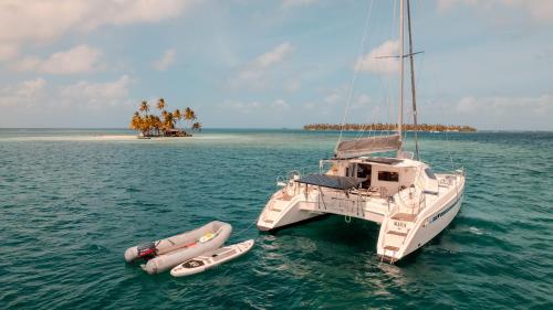 a white boat in the water next to two canoes at Enjoy Sailing Experience in El Porvenir