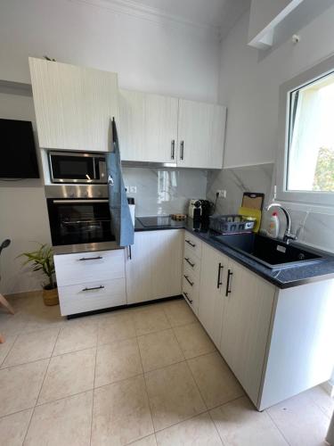 a kitchen with white cabinets and a black counter top at Kos Physis Apartment in Kos Town