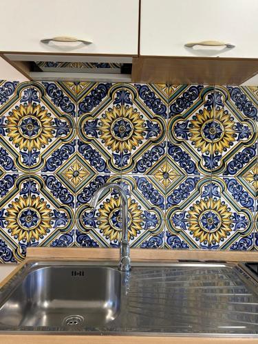 a kitchen sink with a blue and white tile wall at BM Flowers in Tropea