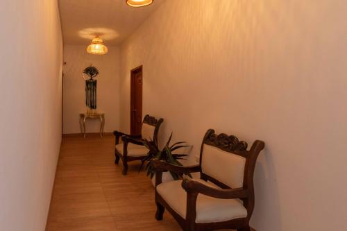 a hallway with three chairs and a table with a plant at Artemisa Hotel Villa de Leyva in Santa Sofía