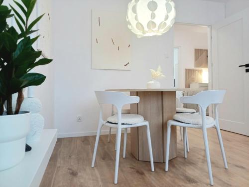a white kitchen with white chairs and a table at Apartament Jadwiga in Biskupiec