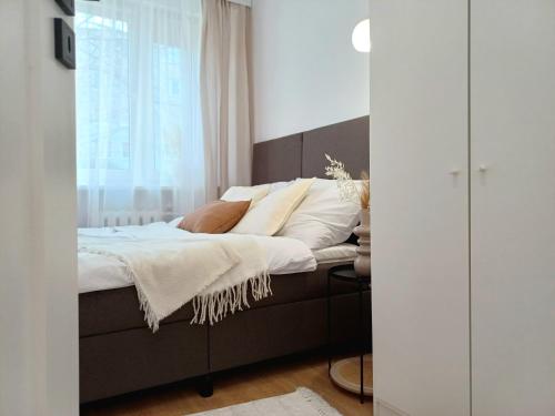 a bedroom with a bed with white sheets and a window at Apartament Jadwiga in Biskupiec