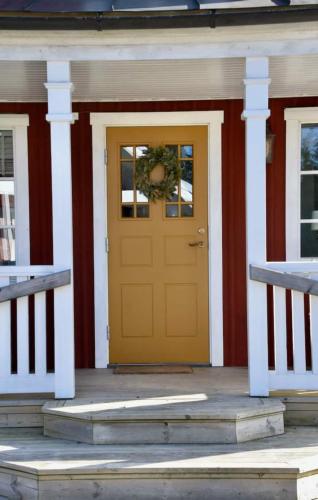 a yellow door on a red and white house at Kopperhemmets Gård in Holmared